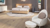 Beiges Polsterbett von Desede Switzerland mit passendem Sessel und Hocker im eleganten Schlafzimmer.