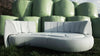 Ein hellblaues Outdoor-Sofa aus Stoff von Desede Switzerland steht vor grünen Ballen.
