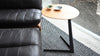 Schwarzes Ledersofa von Desede Switzerland neben Holztisch auf gemustertem Teppich.