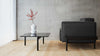 Graues Stoffsofa von Desede Switzerland neben schwarzem Couchtisch mit Vase.