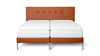 Bett von Desede Switzerland mit orangefarbenem Lederkopfteil, silbernen Füßen und weißer Matratze.