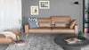 Braunes Ledersofa von Desede Switzerland mit Kissen, vor grauer Wand und Teppich.