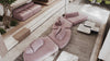 Rosa Stoffsofa von Desede Switzerland mit modularer Form und eleganten Marmortischen im Hintergrund.