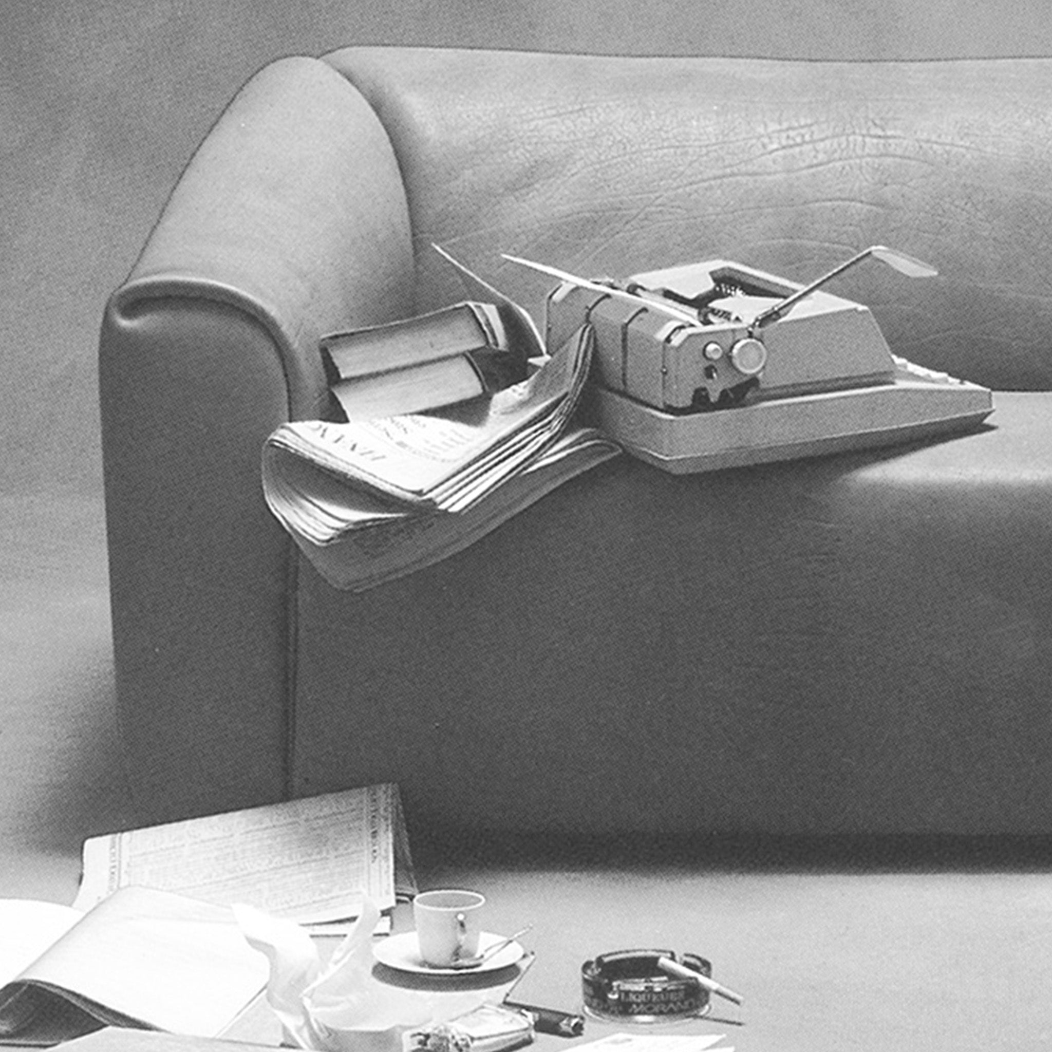 Desede Switzerland Ledersofa in Grau mit Schreibmaschine und Büchern auf der Armlehne.