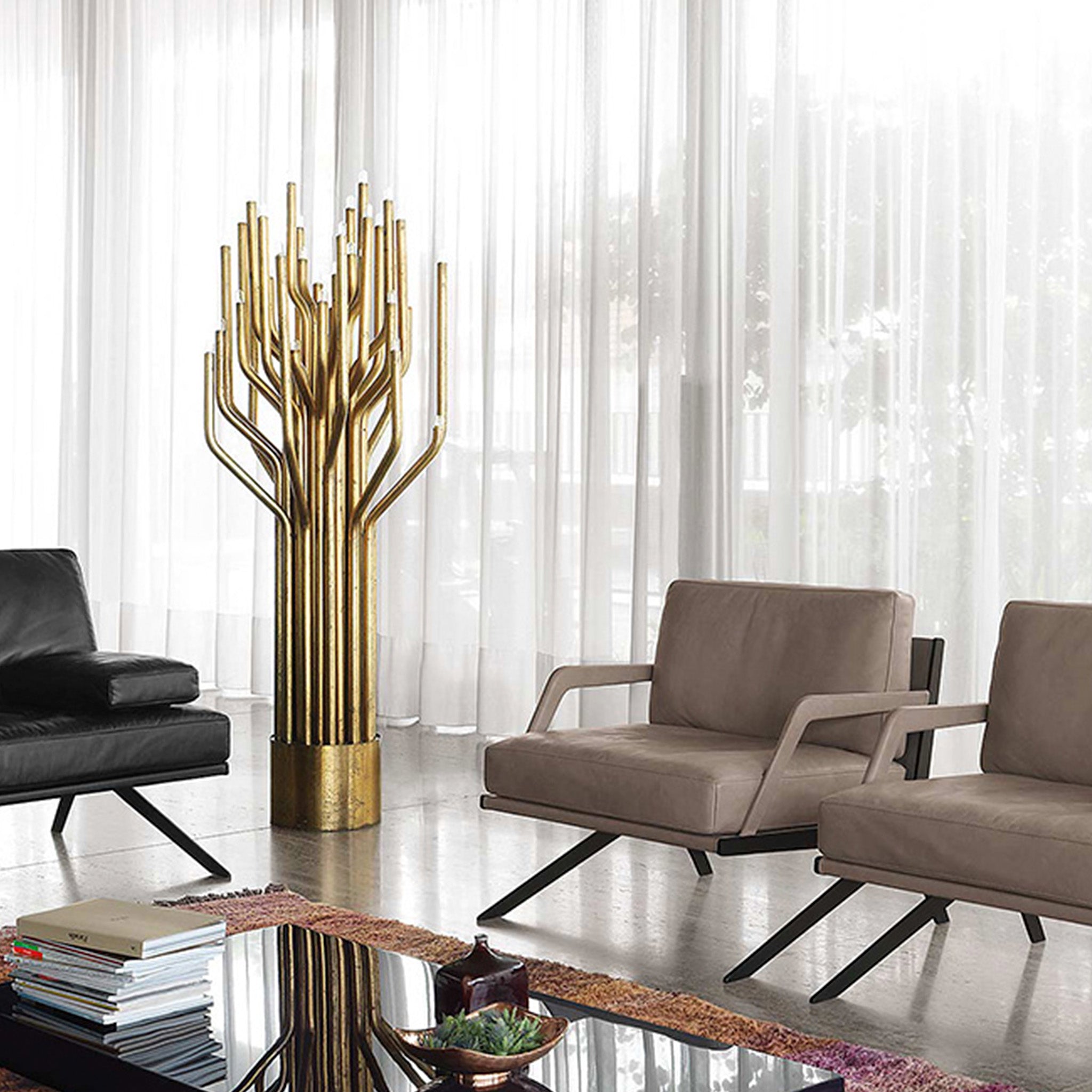 Desede Switzerland Ledersessel in Beige und Schwarz neben goldener Stehlampe im Wohnzimmer.